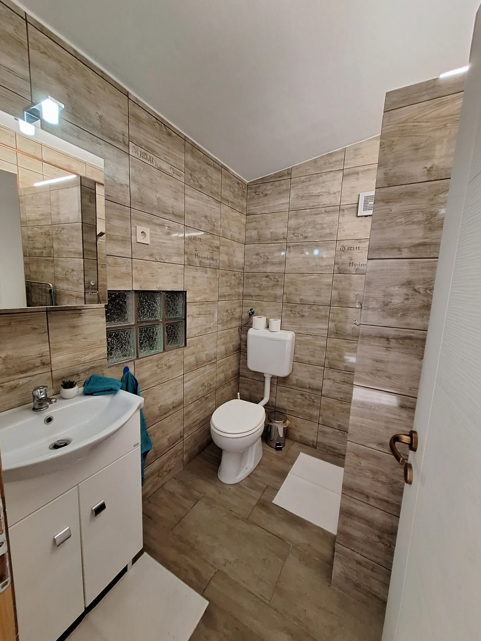 Fa hatású csempés fürdőszoba mosdóval és WC-vel